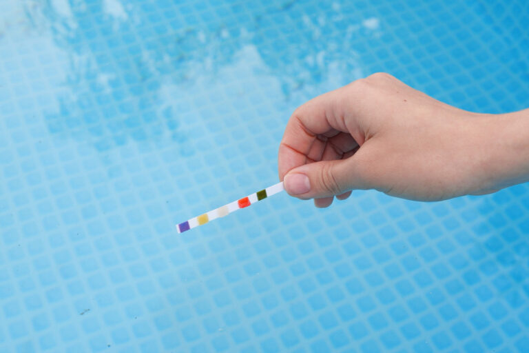 Une personne tenant une bandelette pour analyser le PH et le Chlore de piscine