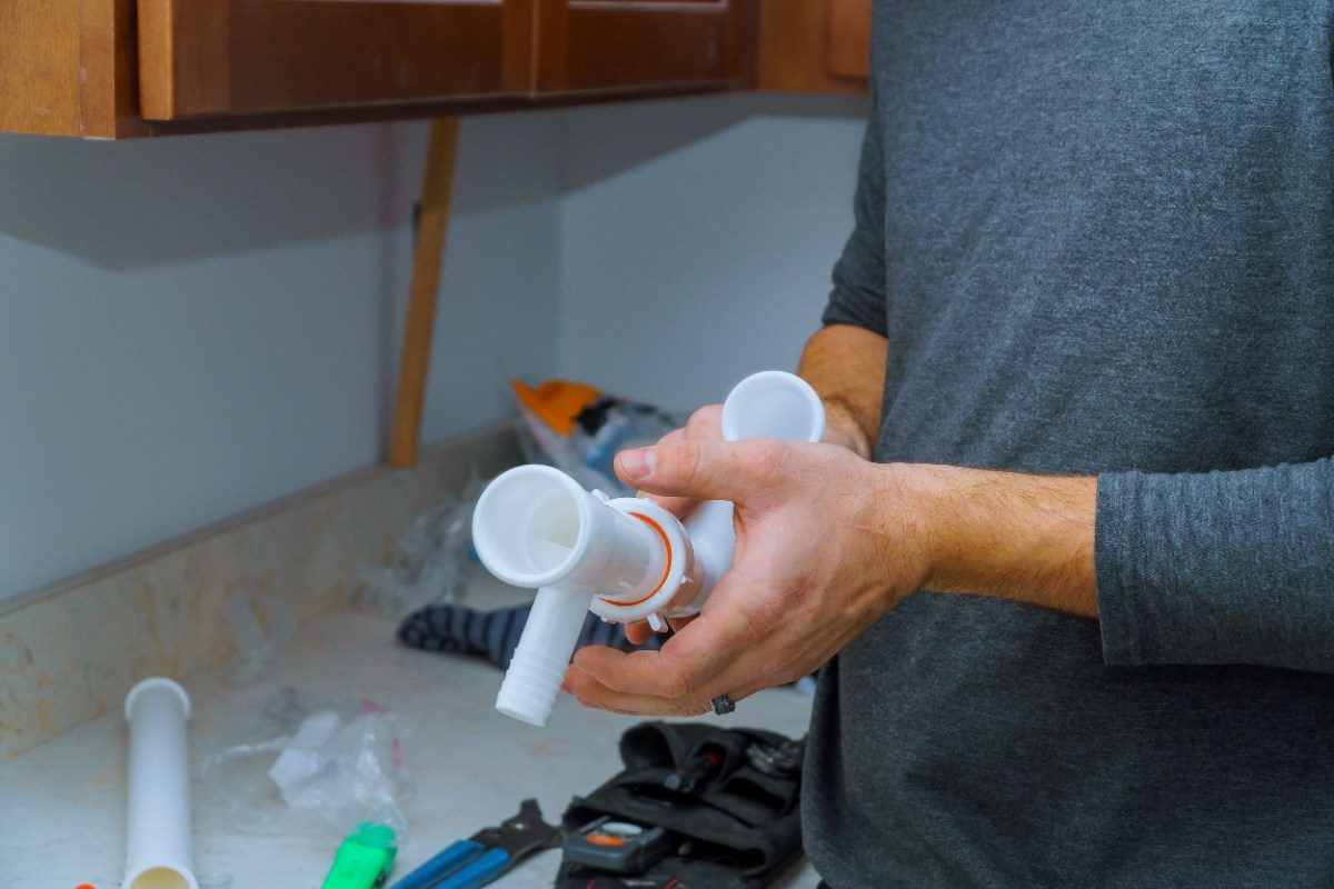 Un homme tenant un tuyau en PVC pour le faire boucher