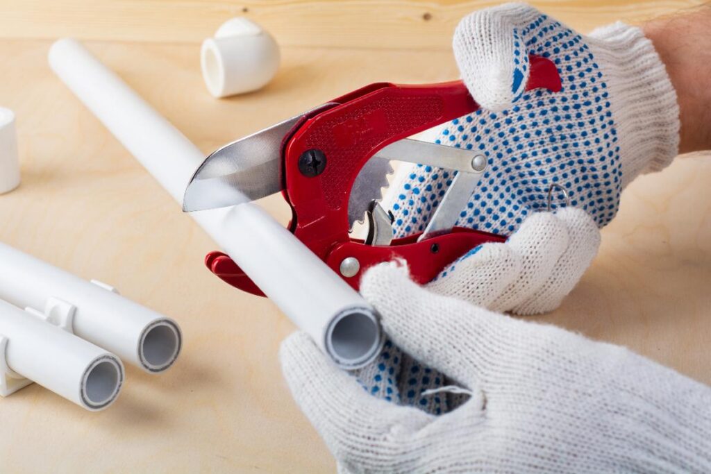Un plombier qui a fini de boucher un tuyau en PVC et refait l'installation