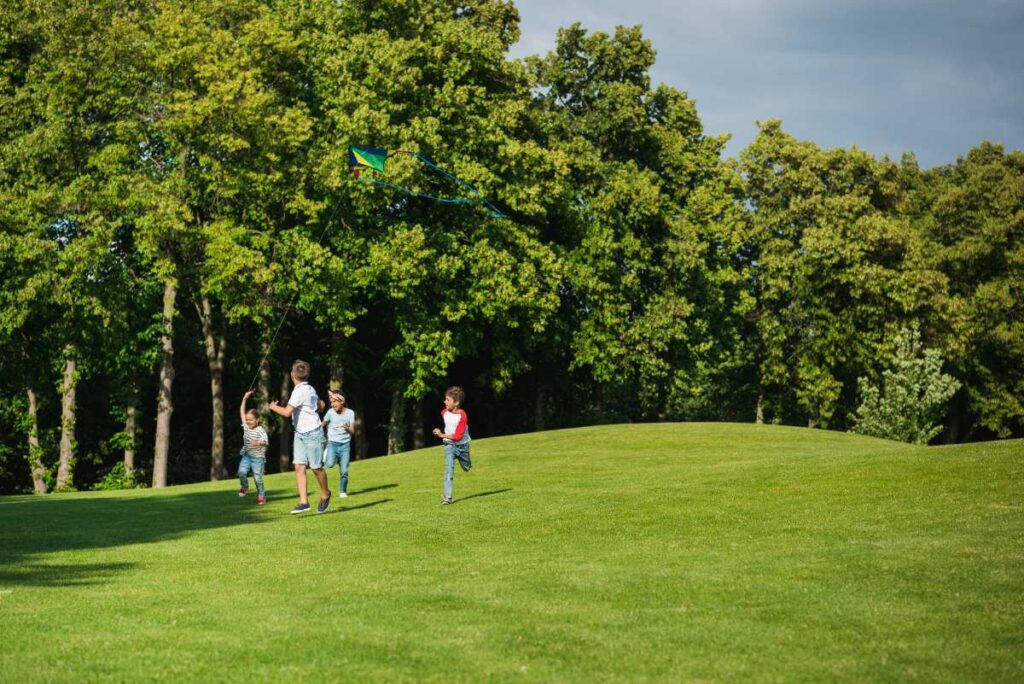 Des enfants qui jouent sur un espace vert près des arbres