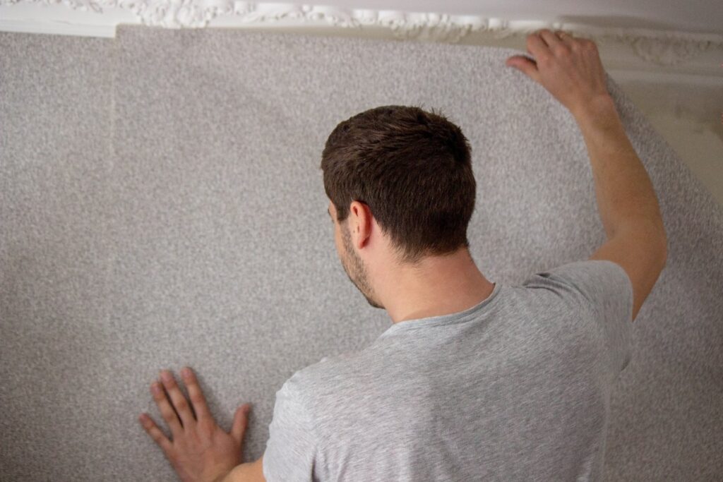 Un homme posant du papier peint sur le mur