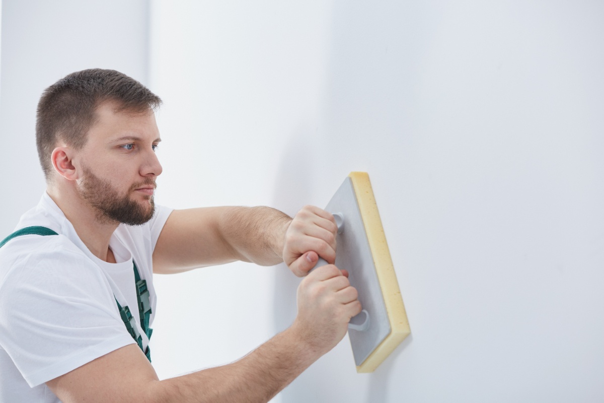 Un homme lissant le mur avec un float
