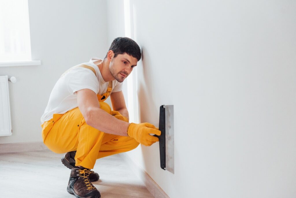Un homme lissant le mur avec une truelle