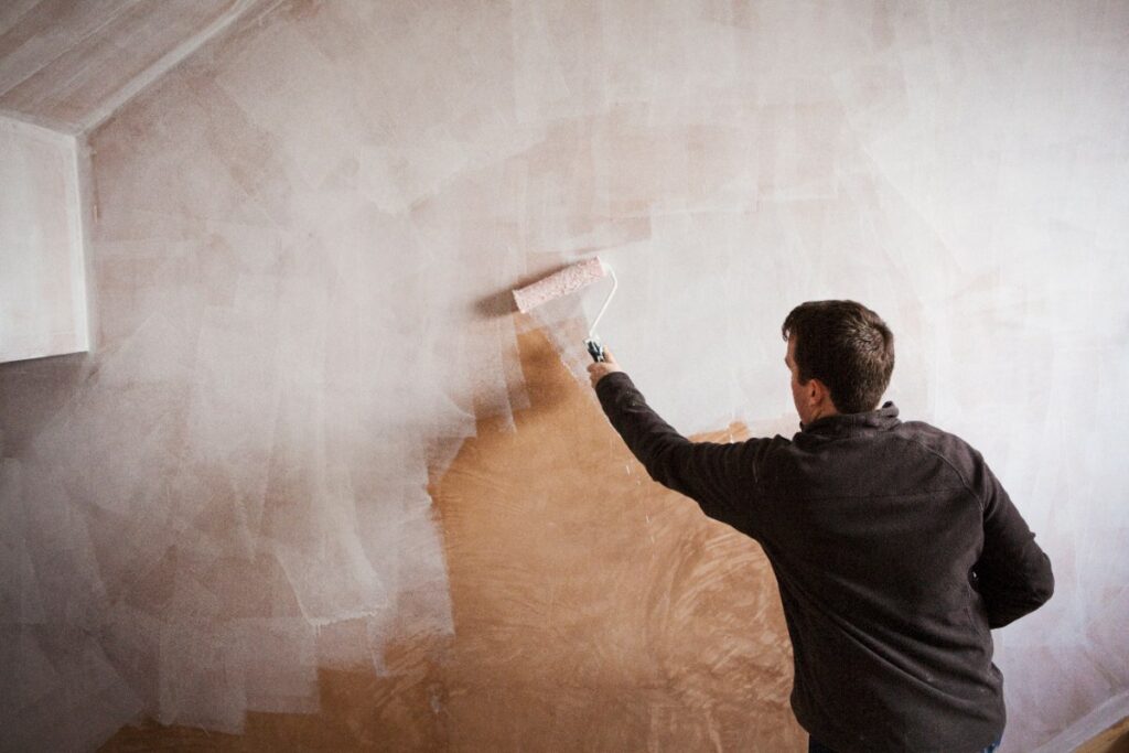 Un homme peignant le mur intérieur avec du rouleau