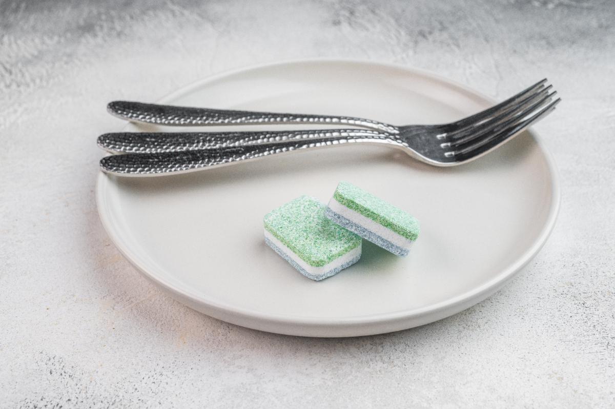 Une assiette avec des fouchettes et des pastilles lave-vaisselle
