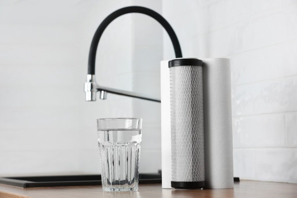 Cartouches filtres à eau et un verre d'eau près du robinet