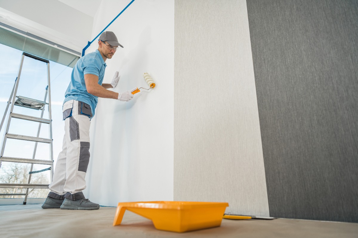 Un homme qui utilise un rouleau pour peindre le mur