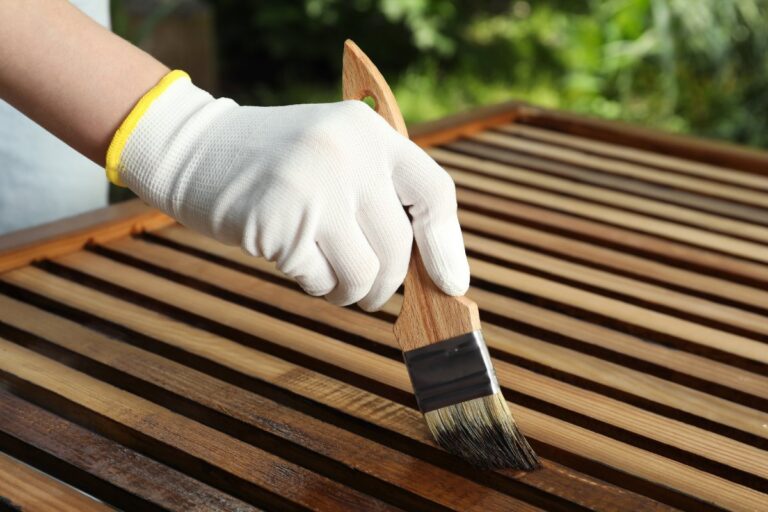 Main gantée appliquant de la teinture sur une surface en bois