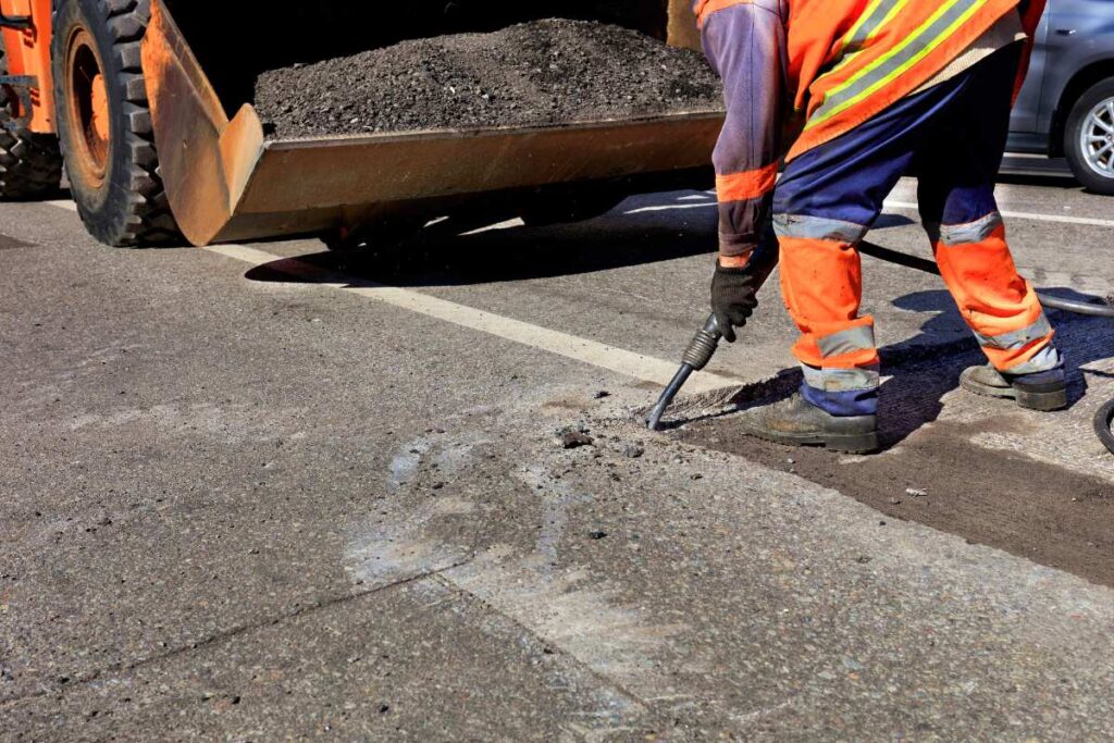 Un ouvrier qui déblaie du morceau d'asphalte sur la route