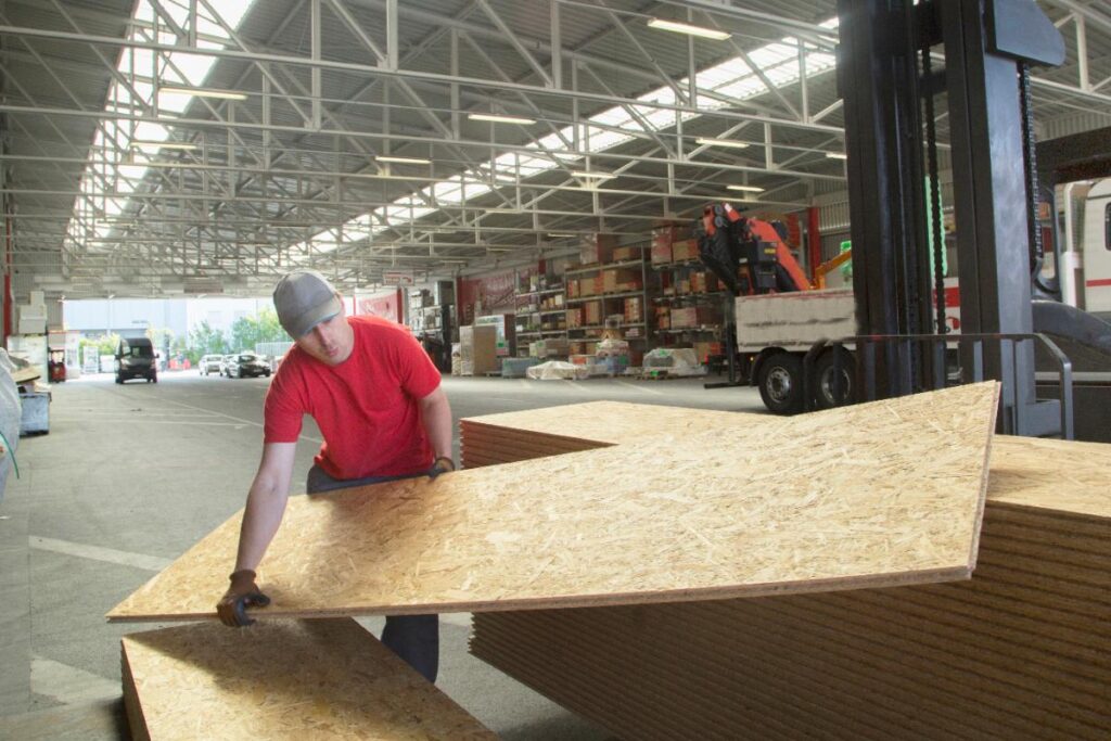 Un ouvrier qui porte un panneau OSB