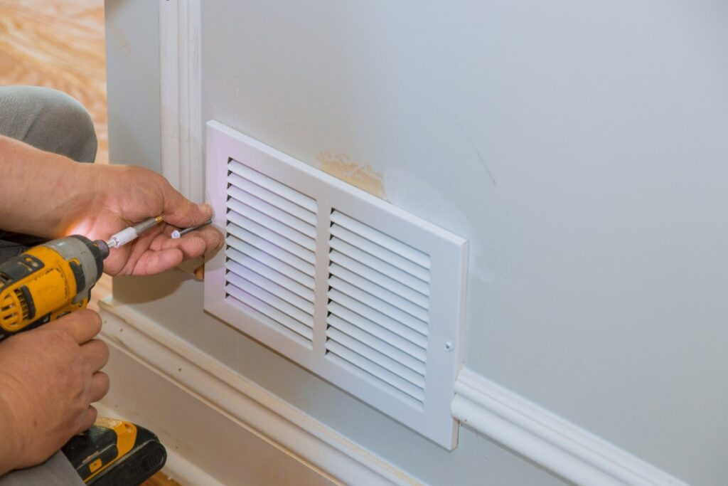 Une personne installant un couvercle de ventilation
