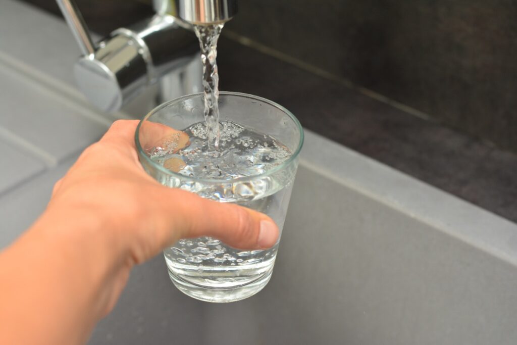 Une personne qui remplie un verre d'eau au robinet