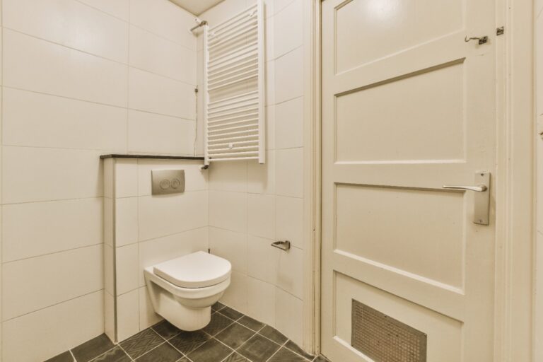 Une toilette avec un mur en carrelage blanc