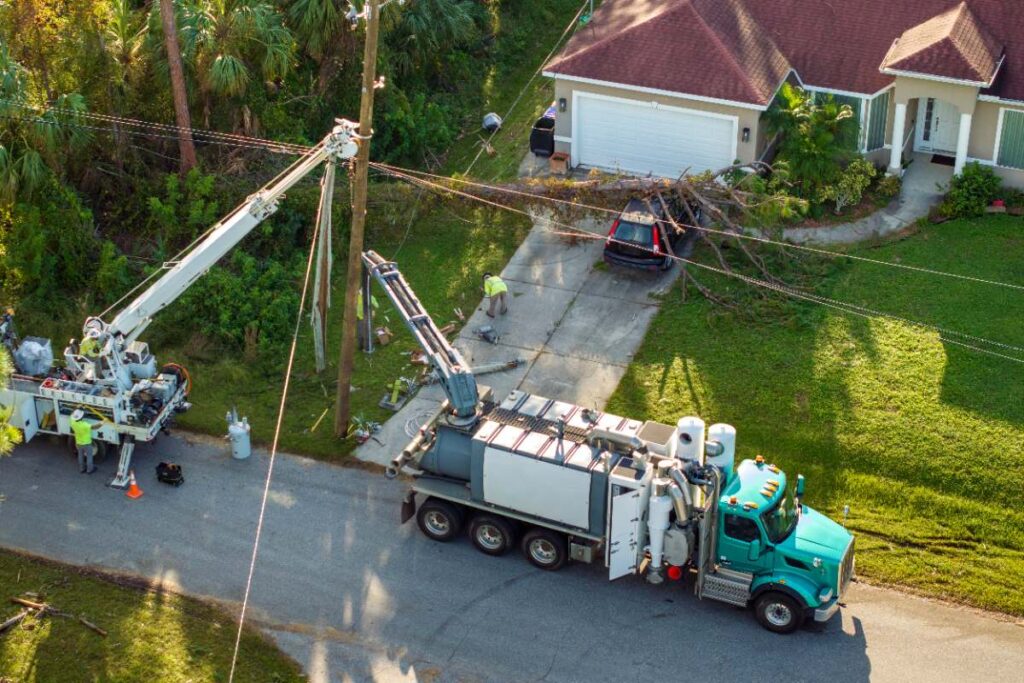 Professionnels faisant une installation de poteau EDF devant une propriété