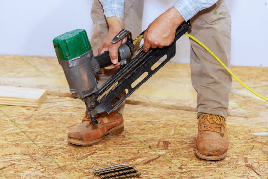Un ouvrier utilisant du pistolet à clous pour fixer le plancher