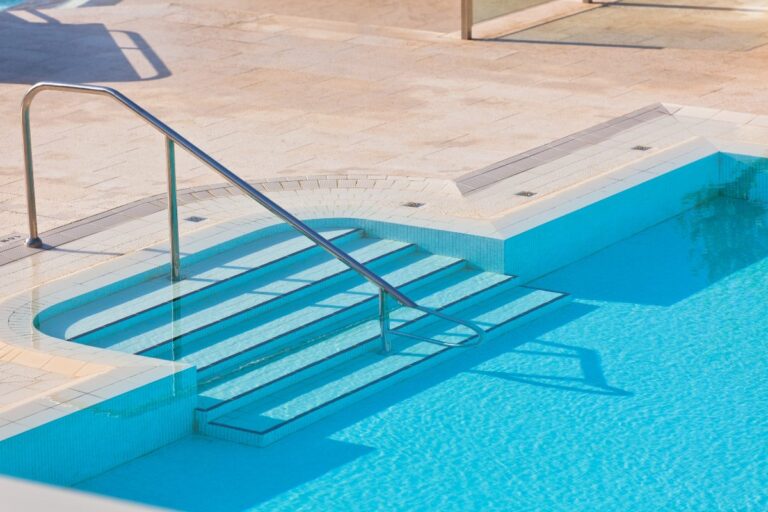 Une piscine installée dans un jardin avec un escalier en béton